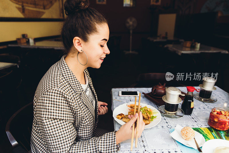 年轻女子下班后休息，在餐厅吃亚洲菜