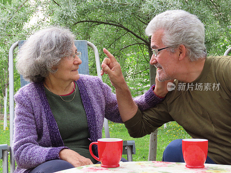 一对活跃的老夫妇在房子的后院喝清晨咖啡