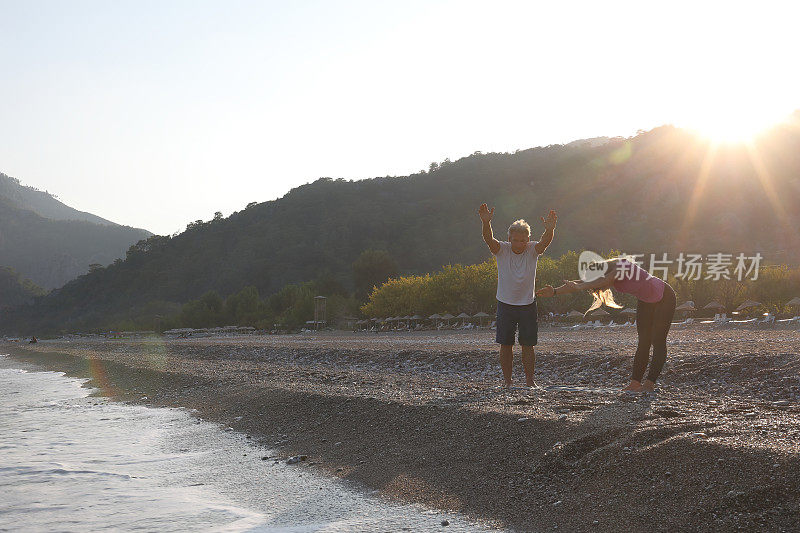 朋友们在日出的时候在海滩上做瑜伽
