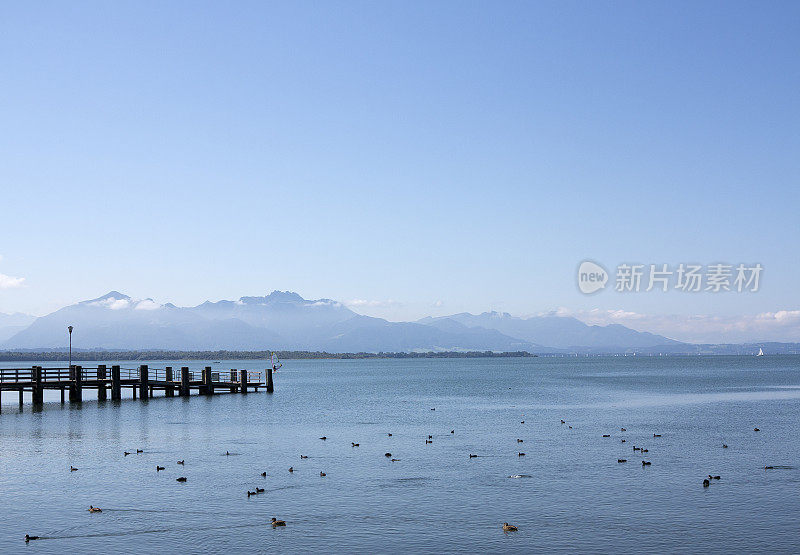 木制的防波堤通向基姆湖，背景是德国的阿尔卑斯山