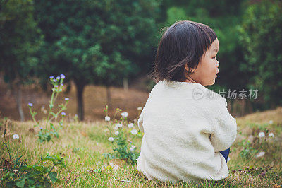 一个中国女孩坐在花园里的草地上