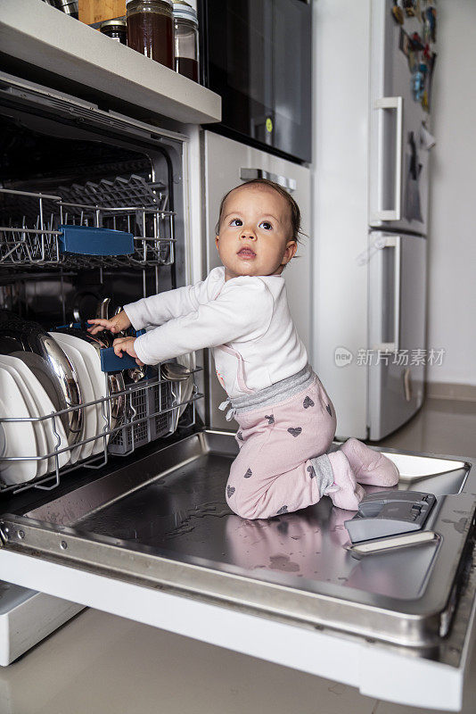 蹒跚学步的小女孩在帮着卸载洗碗机