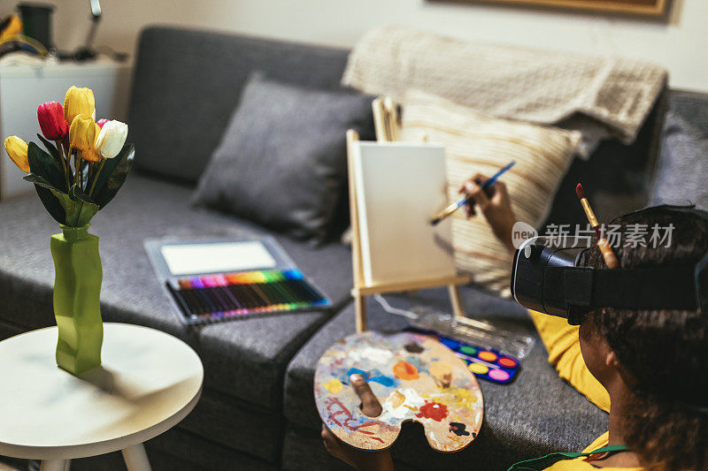 快乐的黑人女学生在家里用画笔画画，用VR眼镜让自己沉浸在元世界中