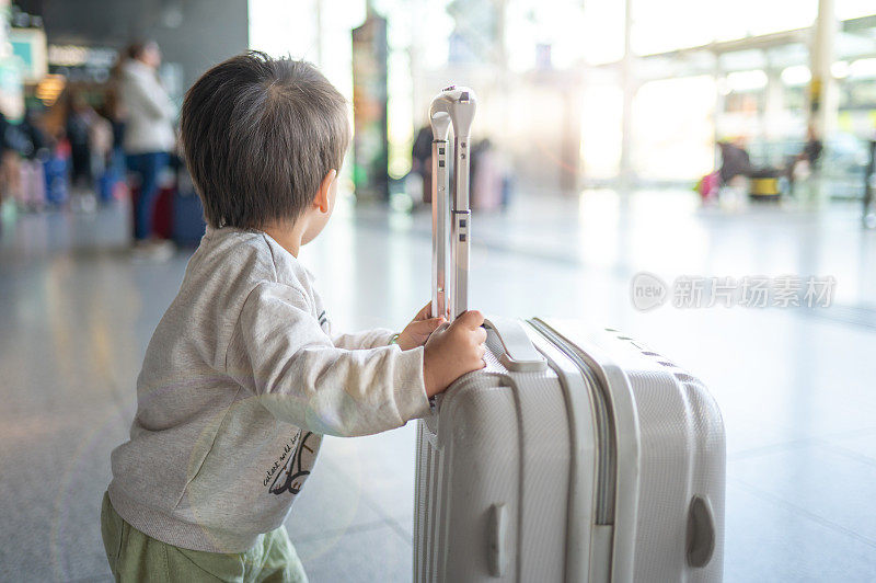 可爱的小男孩推着一个小旅行袋在不明的机场