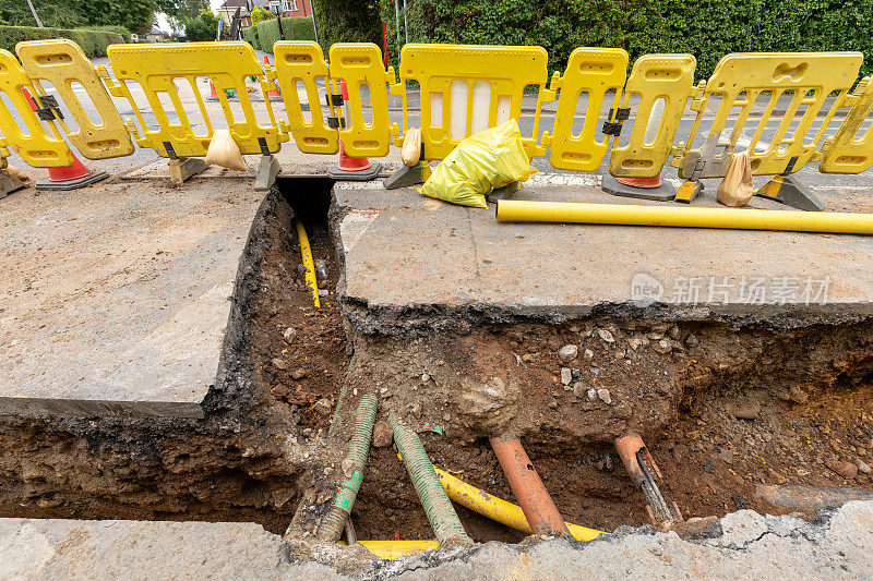 英国的道路工程正在挖掘当地的柏油路面，以修复地下的公用管道，并设置安全屏障和标志