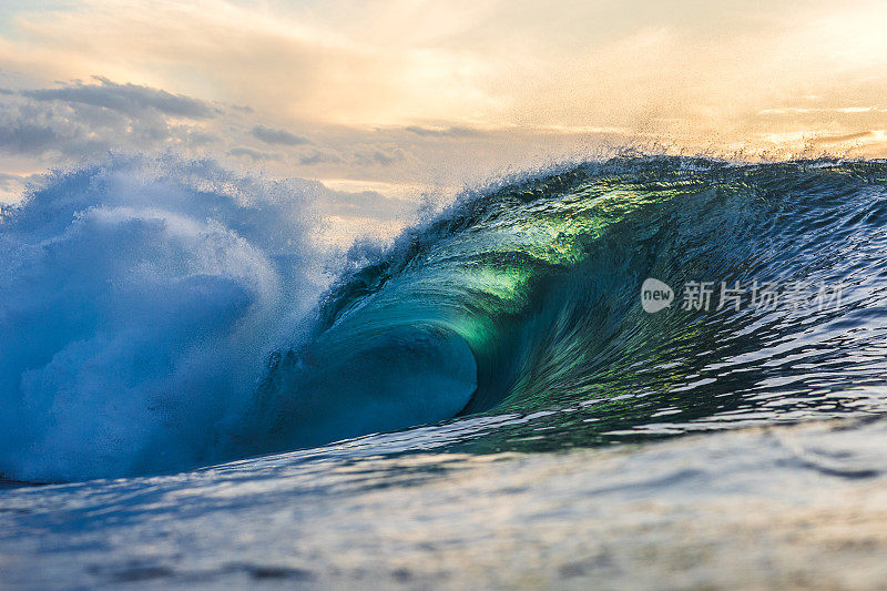 近景，翠绿的波浪在金色的光线下冲破海洋