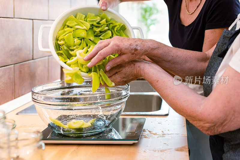 家庭厨房里的成熟女人帮老妈妈清洗青椒做自制的蔬菜蜜饯