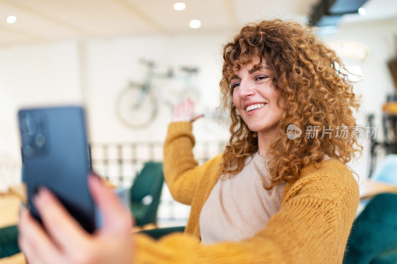 年轻女子坐在咖啡店用手机打视频电话