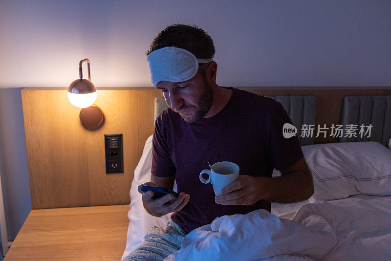 夜间难以入睡的男性在床上使用手机，睡眠障碍和失眠