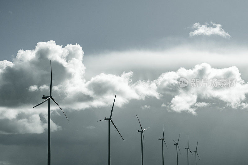 旋转叶片的风力涡轮机，背景是暴风雨般的蓝天。