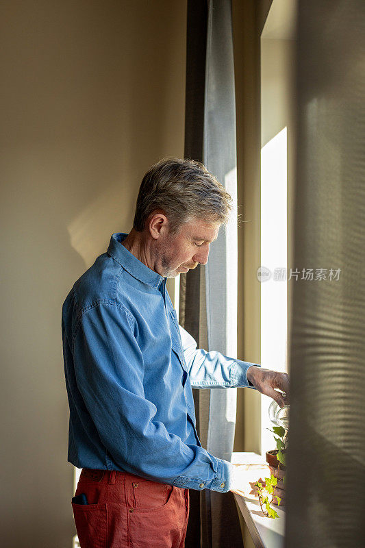 50岁的男人在给家里的植物浇水