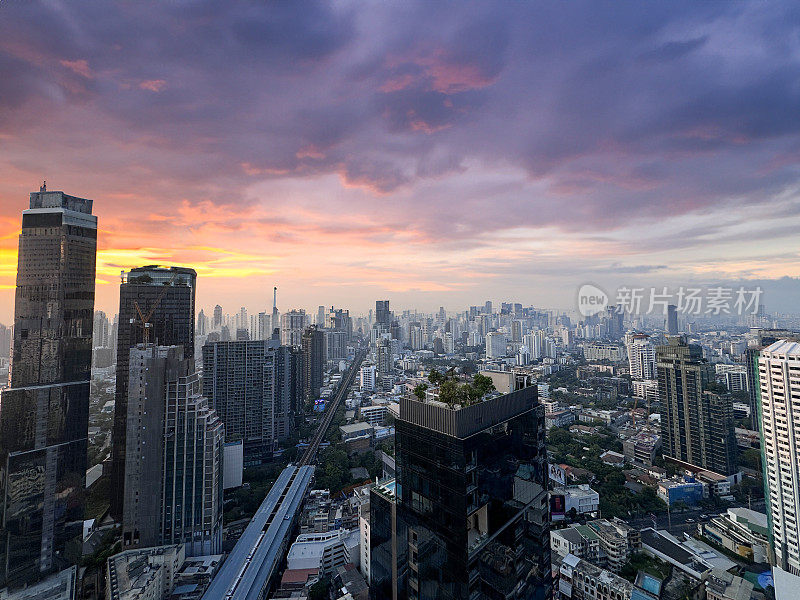 泰国曼谷市中心城市景观摩天楼天际线的特写图片，戏剧性，喜怒无常，大气，橙色和紫色的日落，多云的天空