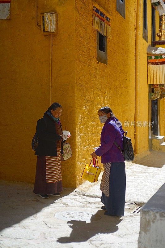 拉萨，中国——2024年3月27日:两名女朝圣者在色拉寺准备酥油。