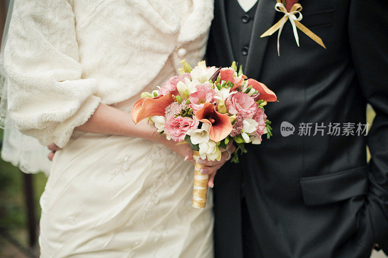 一对新婚夫妇与新娘的橙马蹄莲花束