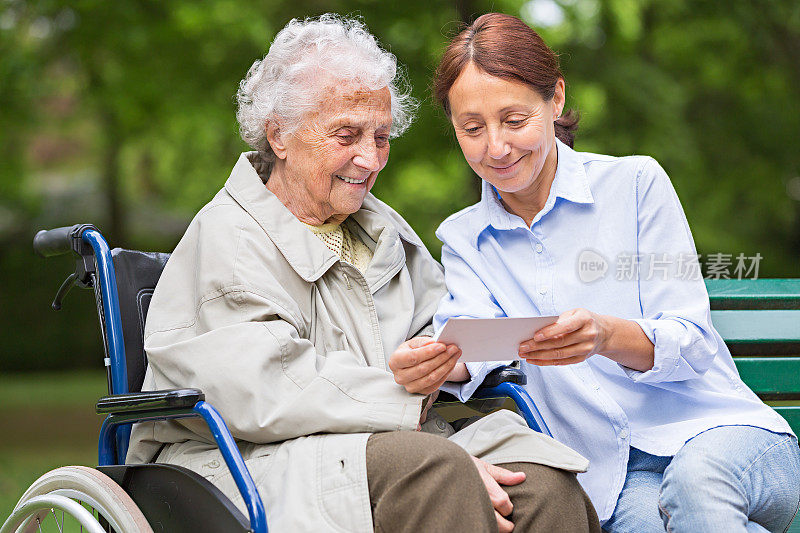 坐在轮椅上的老年妇女和户外的家庭护理员