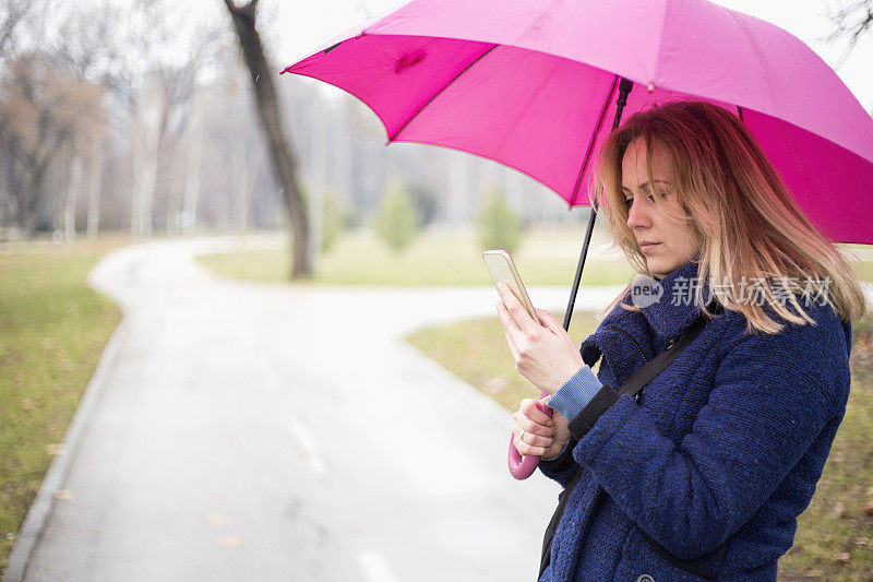 年轻女子与手机在雨天