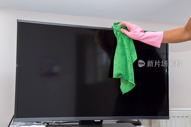 手戴防护手套仔细清洁电视屏幕上的灰尘。