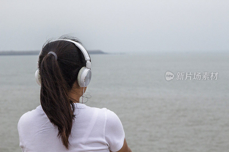 女孩戴着耳机，面朝大海