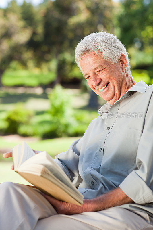 老人笑着读着一本书
