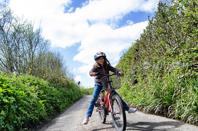 女孩骑着自行车在乡间小路上