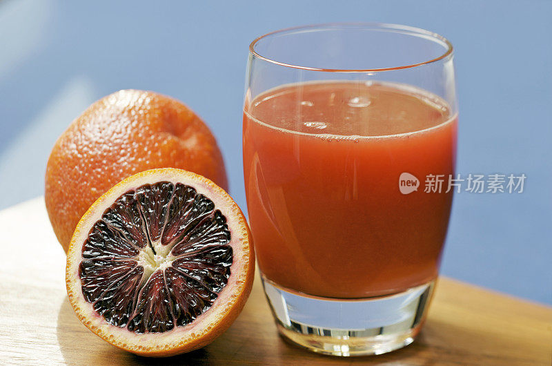 一杯新鲜血橙汁，切片，蓝色背景