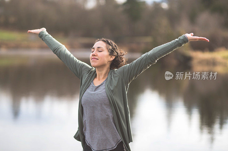 年轻的妈妈在湖边做瑜伽