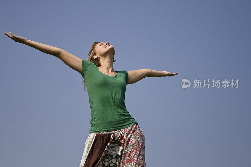 年轻女子举起双手望向天空。