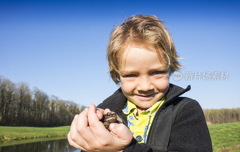 小男孩抱着一只青蛙。