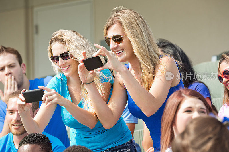 激动的球迷在比赛期间在体育场用手机拍照