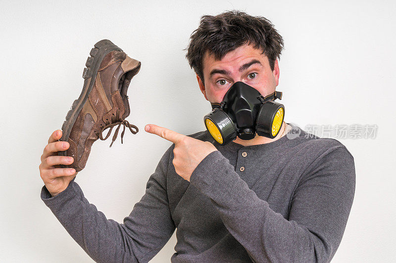 一个戴着防毒面具的人拿着一只又脏又臭的鞋