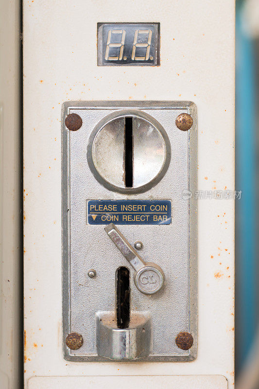 特写的一个金属硬币插槽硬币从一个硬币操作的机器与一个入口和出口槽