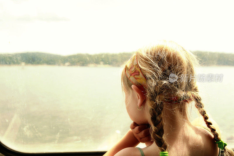 一个小女孩从船窗往外看。