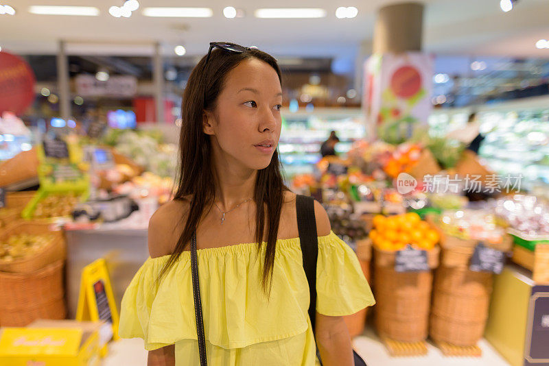 年轻美丽的多民族旅游女人的肖像徘徊在商场在泰国曼谷