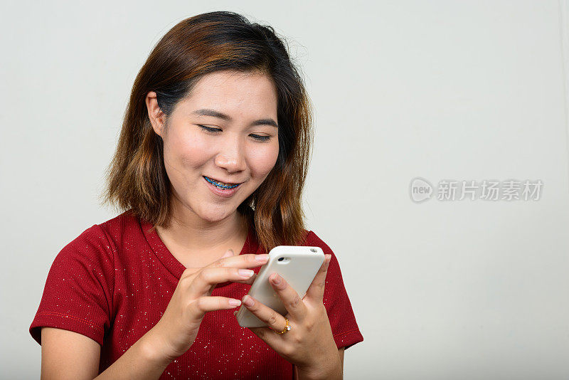 年轻的亚洲女性在白色背景下使用手机