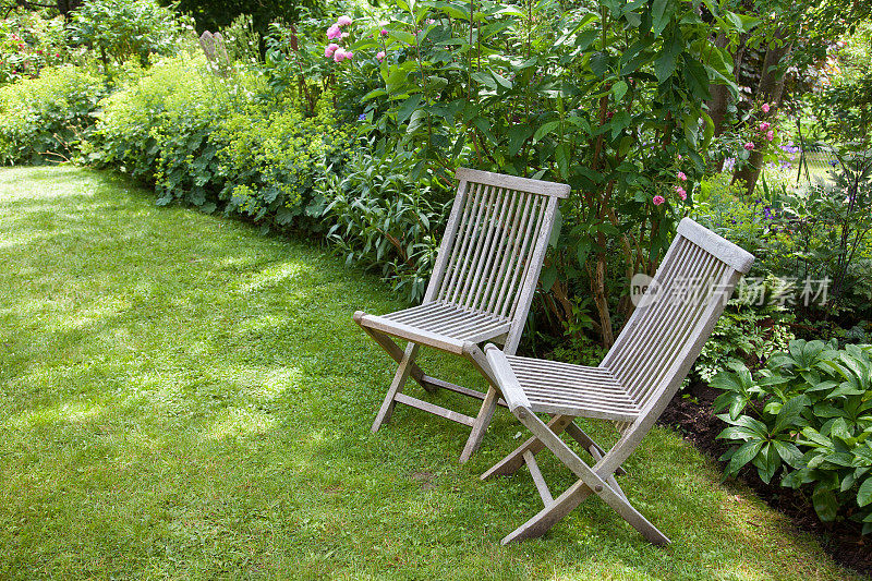 花园里的草坪上放着两把可折叠的木椅