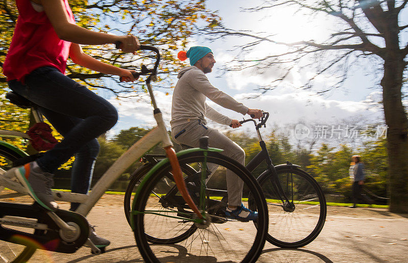 在阳光明媚的日子里，一个年轻帅气的男子在公园里骑自行车。