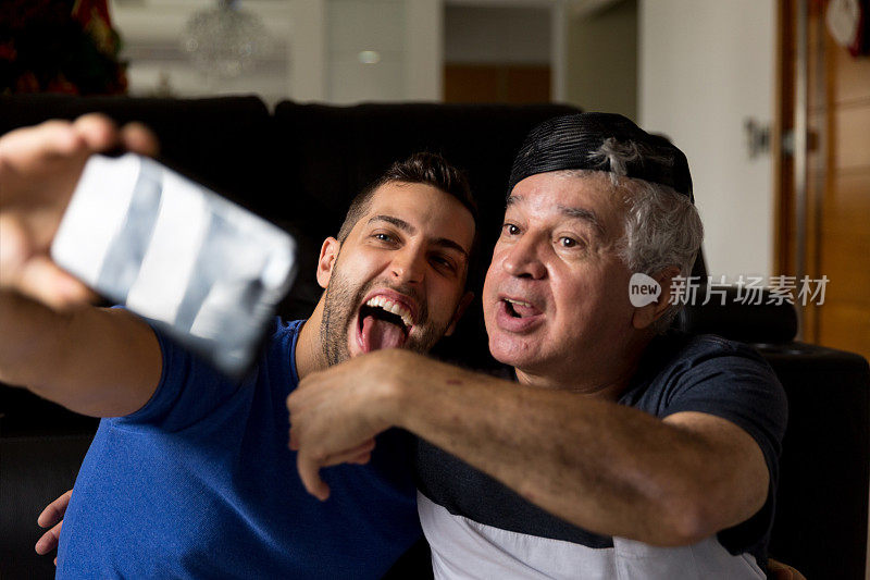爸爸和儿子在家用智能手机在社交媒体上分享