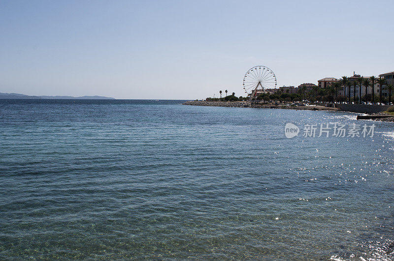 科西嘉岛:位于阿雅克肖城市海滩的地中海清澈的海水，可以看到海岸线上的摩天轮
