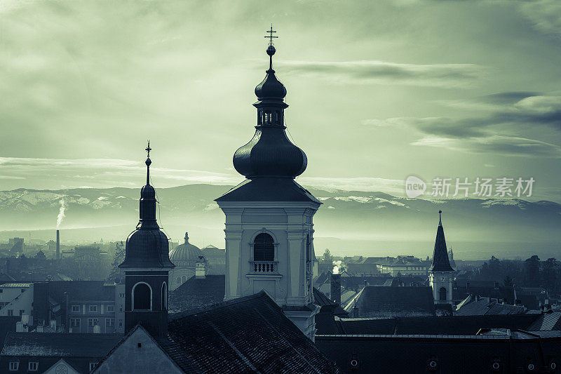 罗马尼亚特兰西瓦尼亚西比乌的城市天际线，远处是教堂尖顶和白雪皑皑的喀尔巴阡山脉