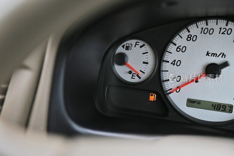 驾驶汽车与数字油汽油水平标志上的仪表板表明油燃料正在运行的低。