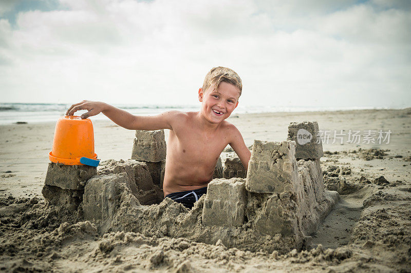 金发男孩在沙滩上建造沙堡