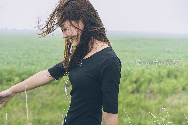 在绿色的田野里听音乐的女人