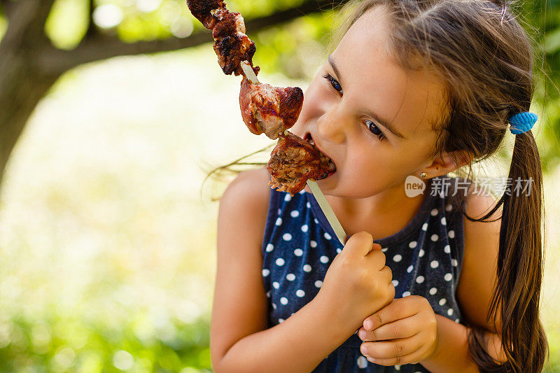 小女孩愉快地吃着羊肉串