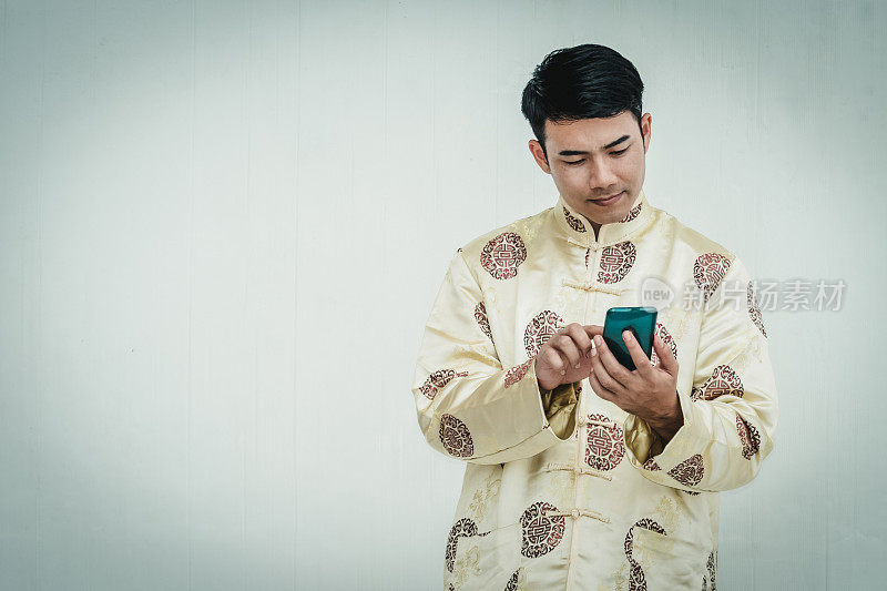 亚洲男人拿着智能手机拿着旗袍。