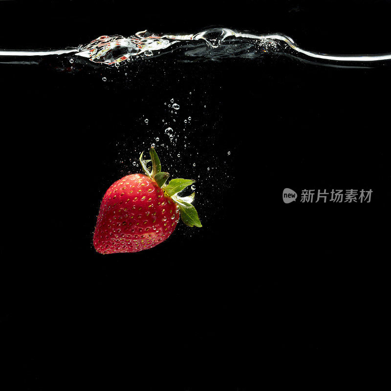 一颗新鲜的草莓被丢入水中。