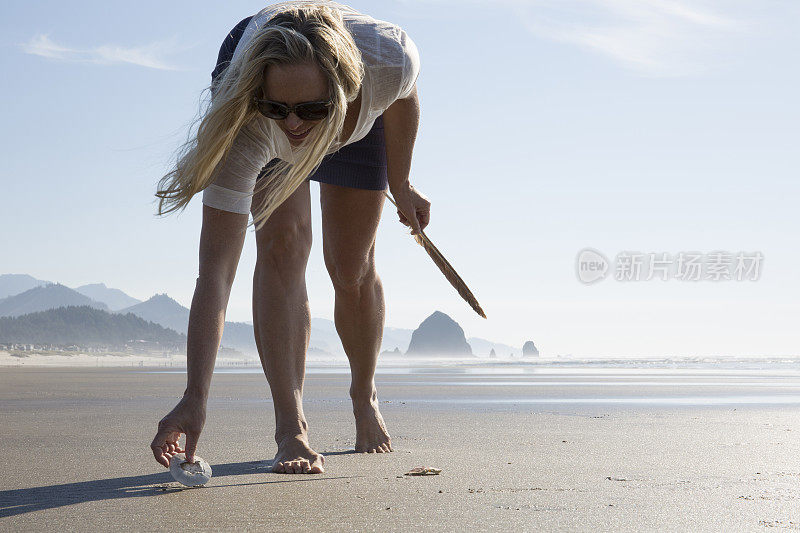 一个女人在空旷的海滩上收集贝壳