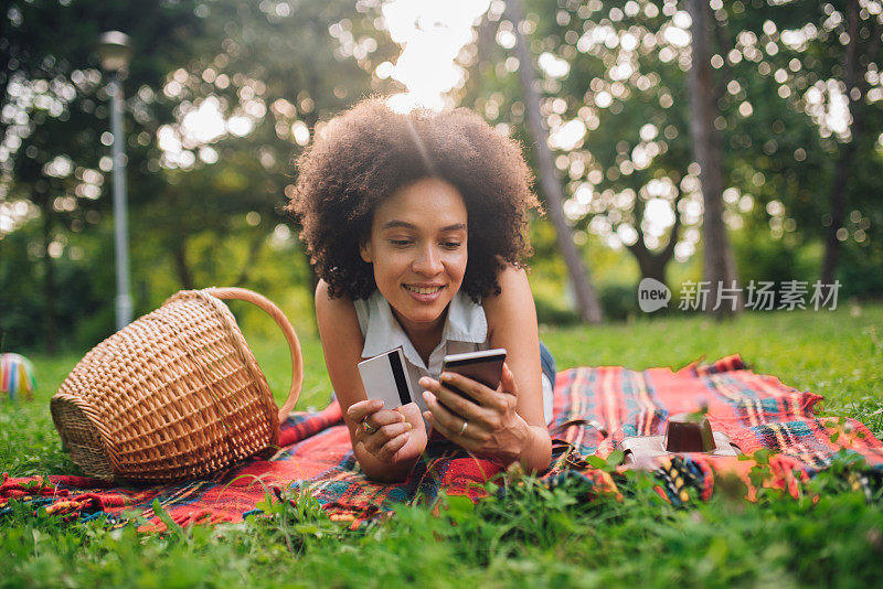 快乐的女人用信用卡和手机在网上购物