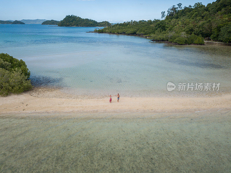 这是一对年轻夫妇在菲律宾群岛热带海滩上放松的无人机鸟瞰图。人们旅行豪华度假目的地的概念