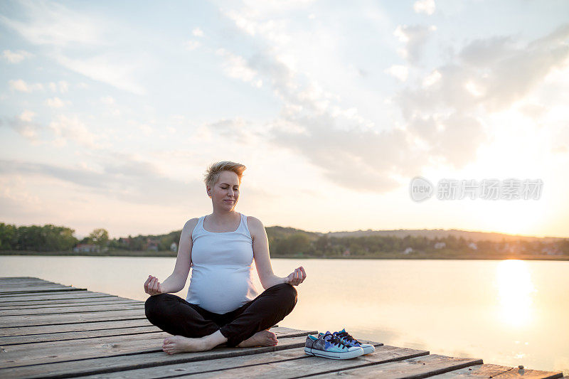 怀孕。怀孕的女人。夕阳在背景中。在水中。