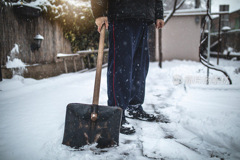 老人拿着一把雪铲